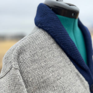 Gray knitted sweater with a blue collar on a mannequin against a blurred background