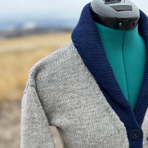 Gray cardigan with navy collar and trim on a mannequin against a blurred natural background