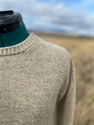 Beige knitted sweater on a mannequin with a blurred natural landscape background